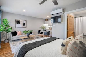 Een moderne slaapkamer met een bed, een bureau, een bank en een eettafel.
