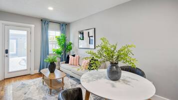 A modern living room with a sofa, a round dining table, and two potted plants.