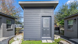 A small, single-story building with a gray exterior, a door, and a small porch area. - Houston Hideaway Near Dwntwn and City Attractions (Houston)