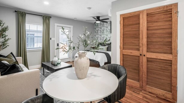 A room with a round table, a vase, a sofa, a bed, and a wooden wardrobe. - Houston Hideaway Near Dwntwn and City Attractions (Houston)