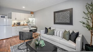 A modern living room with a sofa, coffee table, and a dining area with a table and chairs. - Houston Hideaway Near Dwntwn and City Attractions (Houston)