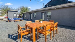 A building with a gravel patio, a wooden table with chairs, a blue sofa set, and a small shed. - Houston Hideaway Near Dwntwn and City Attractions (Houston)