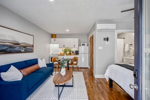A compact living space with a sofa, a dining table, a bed, and a kitchenette. - Urban Studio Retreat Near Downtown Houston (Houston)