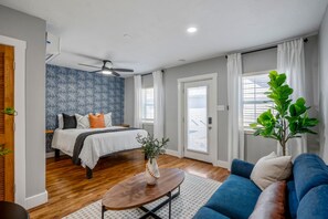 Ein Schlafzimmer mit Bett, Deckenventilator und einem Fenster mit Vorhängen.