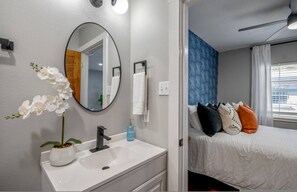 A bathroom with a white sink, a mirror, and a potted orchid. - Urban Studio Retreat Near Downtown Houston (Houston)