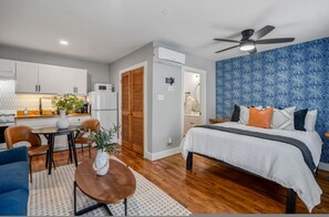 A bedroom with a bed, a ceiling fan, a nightstand, and a wall with a blue pattern. - Urban Studio Retreat Near Downtown Houston (Houston)