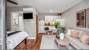 Una habitación moderna con cama, sofá, mesa de comedor y zona de cocina.