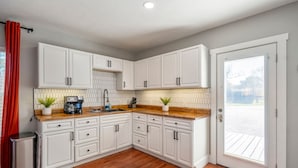 A kitchen with white cabinets, a wooden countertop, a sink, and a potted plant. - 2-bedroom - Equipped Kitchen - Gated Parking (Houston)