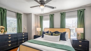 A bedroom with a bed, nightstands, a dresser, a ceiling fan, and green curtains. - 2-bedroom - Equipped Kitchen - Gated Parking (Houston)