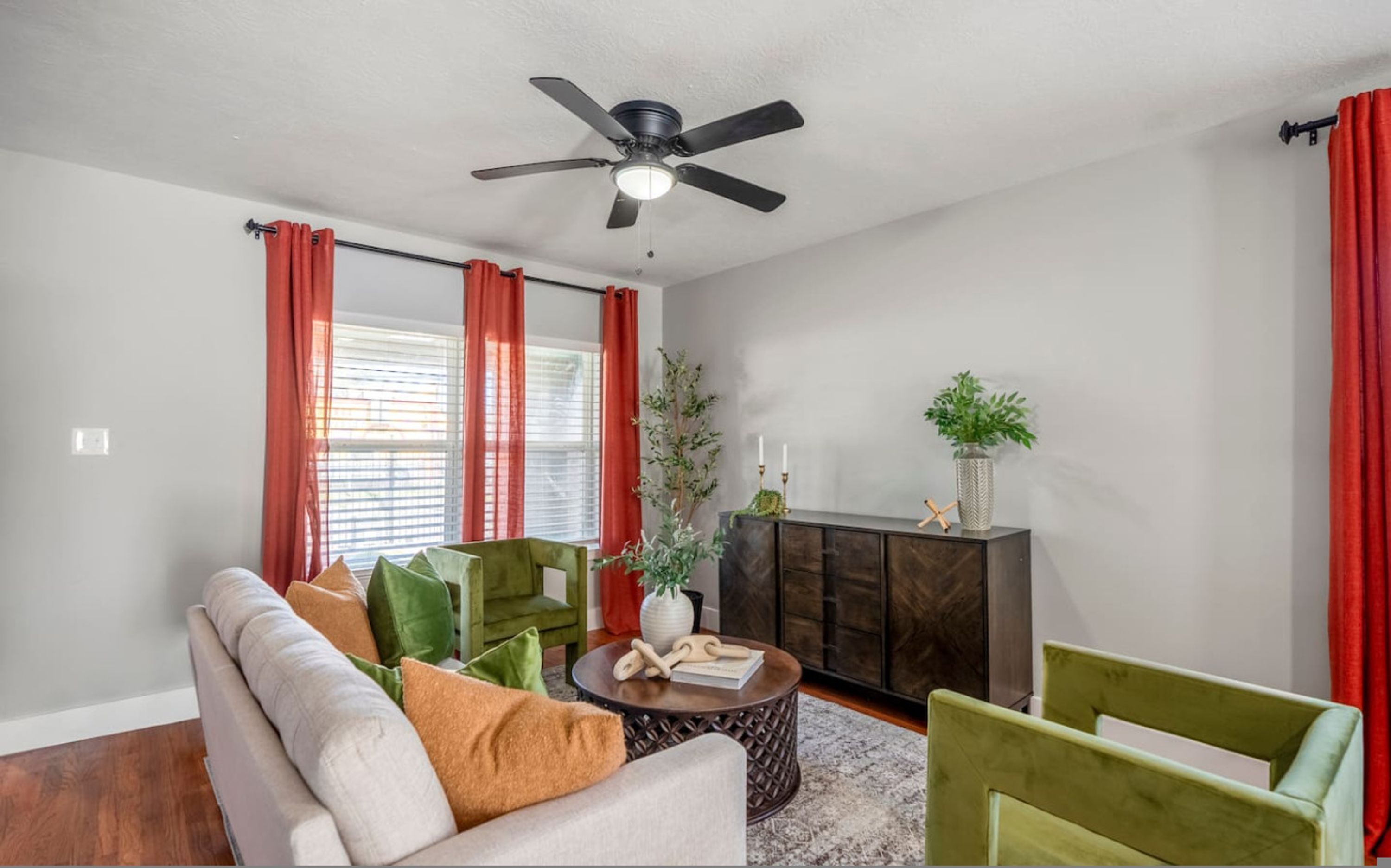 A living room with a ceiling fan, a sofa, chairs, a coffee table, and a cabinet.