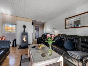 Ein gemütliches Wohnzimmer mit Kamin, Ledersofa und Couchtisch mit Blumenvase.