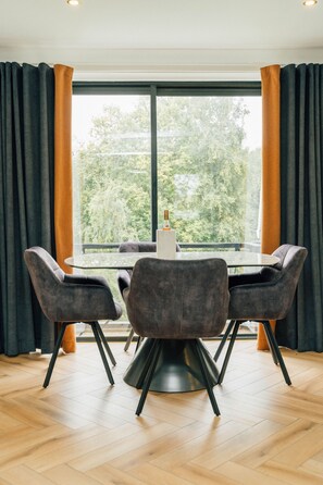 A dining area with a round table, four chairs, and a bottle on the table. - Eagleside Apartments - 21 - sleeps 4 guests  in 2 bedrooms (Auchterarder)