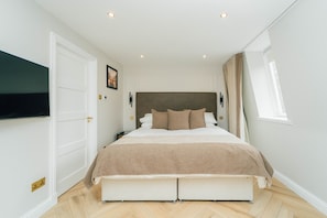 A bedroom with a bed, a television on the wall, and a window. - Eagleside Apartments - 21 - sleeps 4 guests  in 2 bedrooms (Auchterarder)