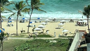 A beach with palm trees, umbrellas, and lounge chairs. - 180-degree sea view (Salvador)