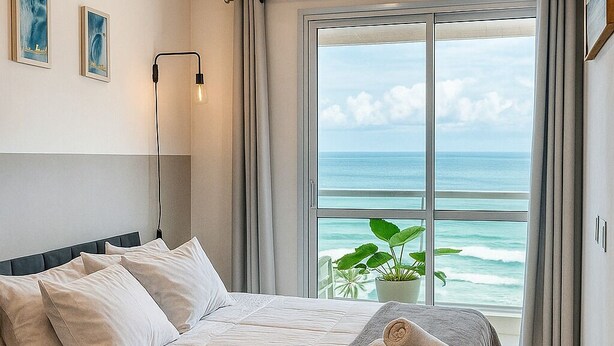 A hotel room with a bed, a potted plant, and a view of the ocean. - 180-degree sea view (Salvador)