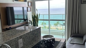 A kitchen with a view of the ocean, a dining area, and a living space. - 180-degree sea view (Salvador)