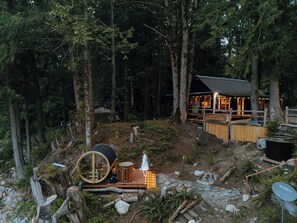 Eine Hütte im Wald mit einer Terrasse, einer runden Struktur und einer Satellitenschüssel.