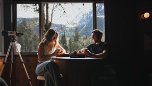 A room with a large window, a tripod, and a table with two people.