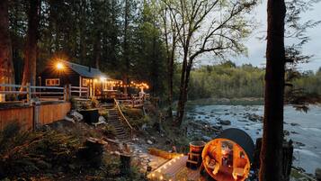 Una baita con veranda, vasca idromassaggio e vista sul fiume.