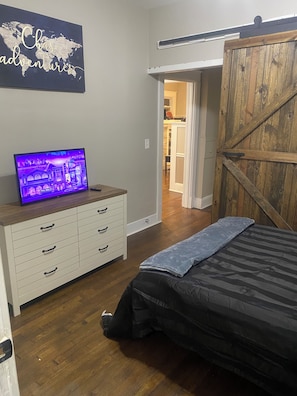 Ein Schlafzimmer mit Bett, Schminktisch, Fernseher und Holztür.