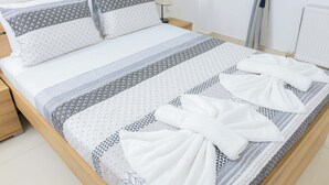 A neatly made bed with patterned bedding and towels, a bedside lamp, and a wooden nightstand. - Thea Villa (Faistos)