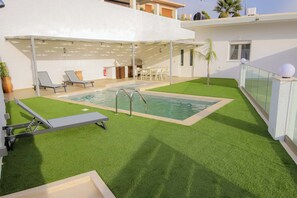 A rooftop pool area with artificial grass, lounge chairs, and a covered seating area. - Thea Villa (Faistos)