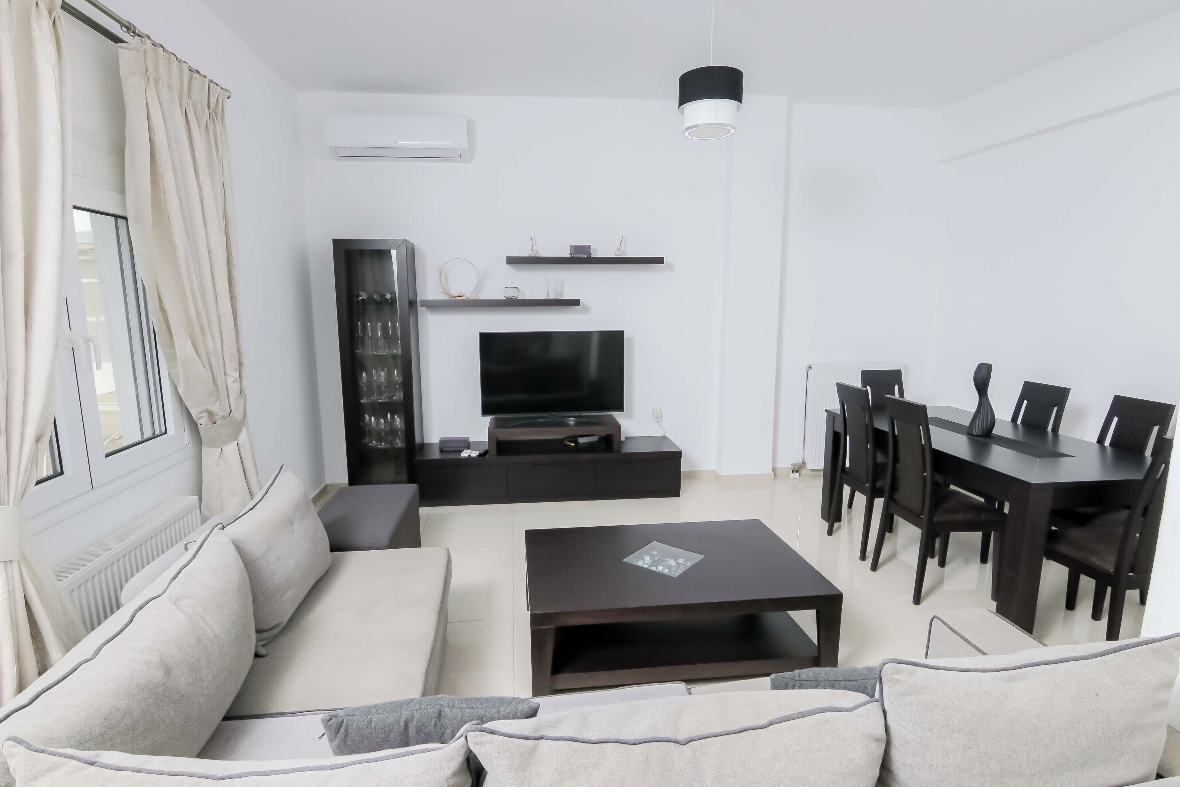 En moderne stue med sofa, sofabord, fjernsyn og spiseområde.
