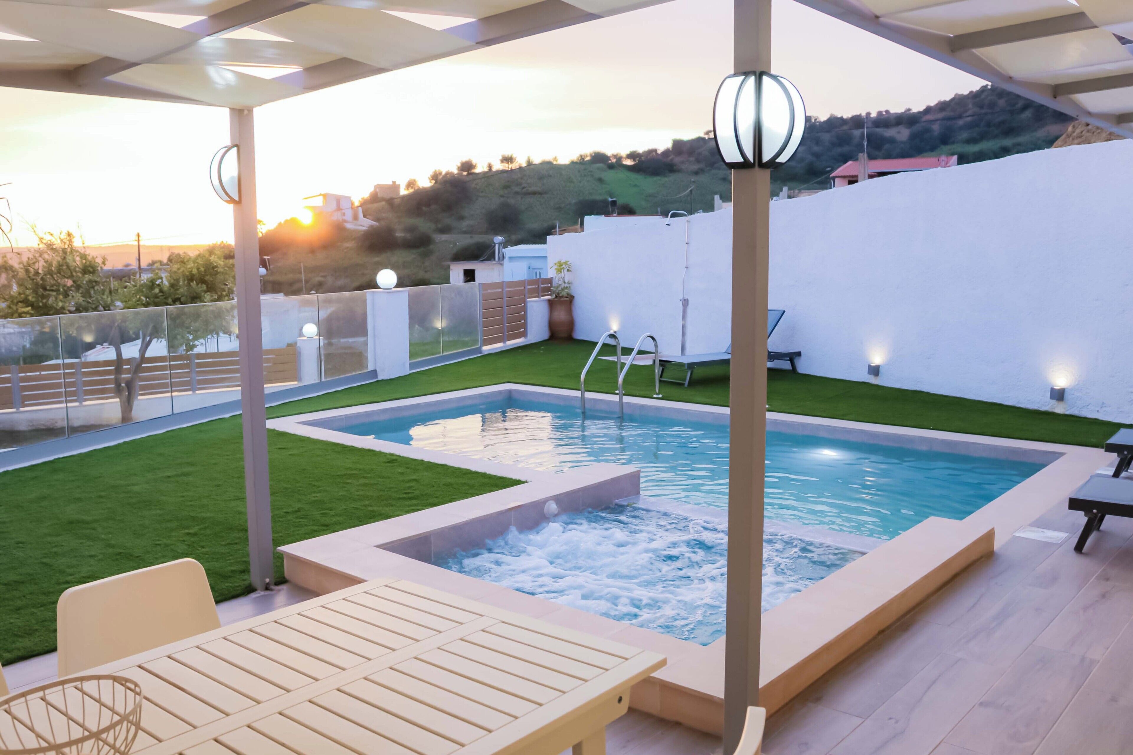 Une piscine sur le toit, avec un jacuzzi, une terrasse ensoleillée et une vue sur une colline.