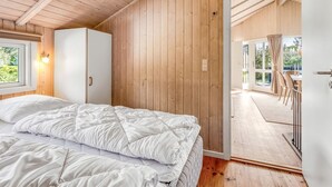 Ein Schlafzimmer mit Bett, Kleiderschrank, Fenster und einer Tür, die auf einen Balkon führt.