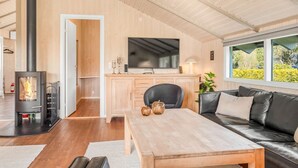 Ein modernes Wohnzimmer mit Kamin, Sofa, Esstisch und Fernseher.