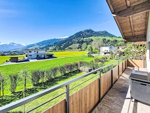 A balcony with a view of a green field, a mountain, and a building. - Apart Wurm by Interhome (Uderns)