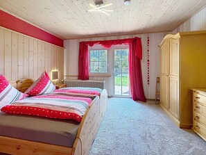 A bedroom with a wooden bed, a radiator, a window with curtains, and a wardrobe. - Scherzingers Fewo by Interhome (Eisenbach)