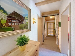 A hallway with a painting, a potted plant, a wooden bench, a door with curtains, and a light fixture. - Scherzingers Fewo by Interhome (Eisenbach)
