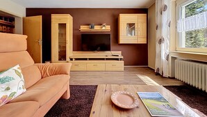 Ein Wohnzimmer mit einer Couch, einem Couchtisch, einem Kamin, Holzkredenzen und einem Fenster mit Blick.