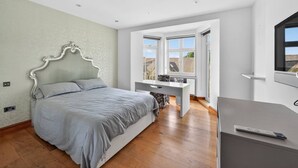 A bedroom with a bed, a desk, and a TV. - Elegant 3 Bed Hampstead Flat (London)