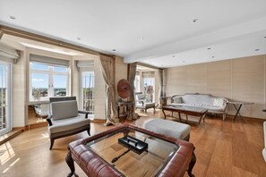 A spacious living room with a leather sofa, a glass coffee table, and a view of the city. - Elegant 3 Bed Hampstead Flat (London)