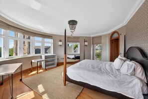 A bedroom with a large bed, a desk, a chair, and a view of the outside. - Elegant 3 Bed Hampstead Flat (London)