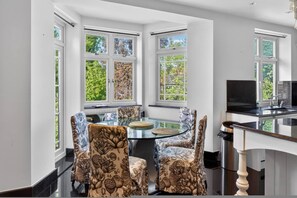A modern kitchen with a glass table, patterned chairs, and large windows. - Elegant 3 Bed Hampstead Flat (London)