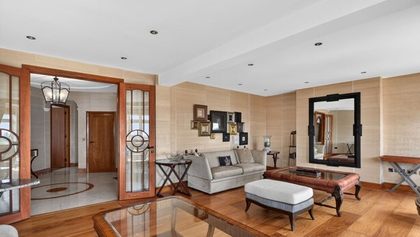 A spacious living room with a sofa, ottoman, and coffee table, a dining area with a glass table, and a hallway with wooden doors. - Elegant 3 Bed Hampstead Flat (London)