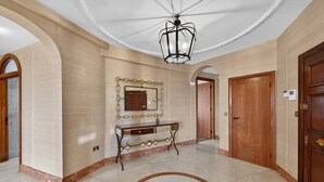 A spacious hallway with a marble floor, a decorative mirror, a wooden door, and a ceiling light fixture. - Elegant 3 Bed Hampstead Flat (London)