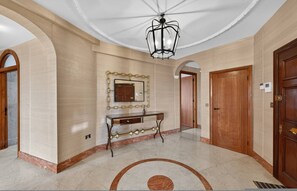 A spacious hallway with a marble floor, a decorative mirror, a wooden door, and a ceiling light fixture. - Elegant 3 Bed Hampstead Flat (London)