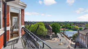 A balcony with a view of a cityscape, including a river, buildings, and trees. - Elegant 3 Bed Hampstead Flat (London)