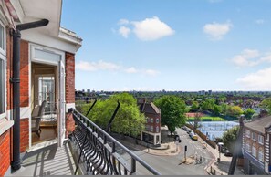 A balcony with a view of a cityscape, including a river, buildings, and trees. - Elegant 3 Bed Hampstead Flat (London)