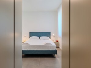 A modern hotel room with a large bed, bedside tables, and a view of the city. - Apartment Renza by Interhome (Colico)