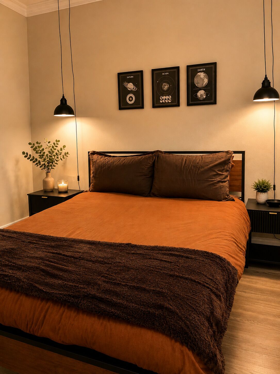 Une chambre à coucher avec un grand lit, deux tables de chevet, une petite table, une lampe fixée au mur et des tableaux représentant des corps célestes.