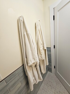 A bathroom with two towels hanging on a wall, a tiled floor, and a door. - Palm Beach Pink House. Walk to restaurants and shops (West Palm Beach)