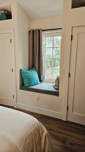 Une pièce avec un coin fenêtre, un lit et une porte.