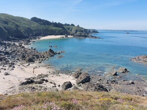 A coastal landscape with rocky shores, clear blue water, and a sandy beach. - Le Vauglin by Interhome (Planguenoual)