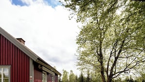 Ein rotes Gebäude mit Terrasse, Außenbestuhlung und einem großen Baum.