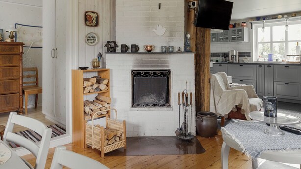 Ein gemütliches Wohnzimmer mit Kamin, Holzmöbeln und einer Küchenzeile mit Schränken und einem Fernseher.